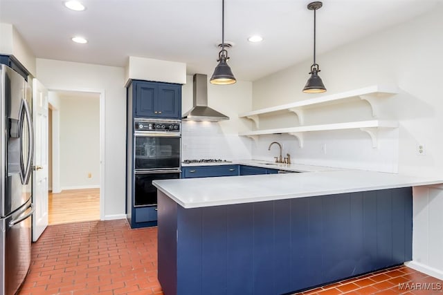 2527 Hermitage Dr, Montgomery, AL 36111 - kitchen featuring wall chimney range hood, blue cabinets, appliances with stainless steel finishes, a peninsula, and open shelves