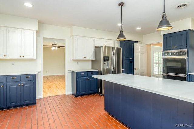 2527 Hermitage Dr, Montgomery, AL 36111 - kitchen with stainless steel fridge, blue cabinetry, light countertops, hanging light fixtures, and white cabinetry