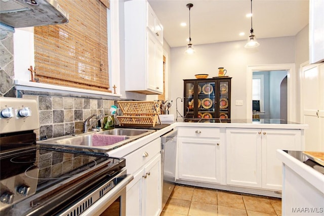 kitchen with stainless steel appliances, white cabinetry, light tile patterned flooring, a peninsula, and arched walkways
