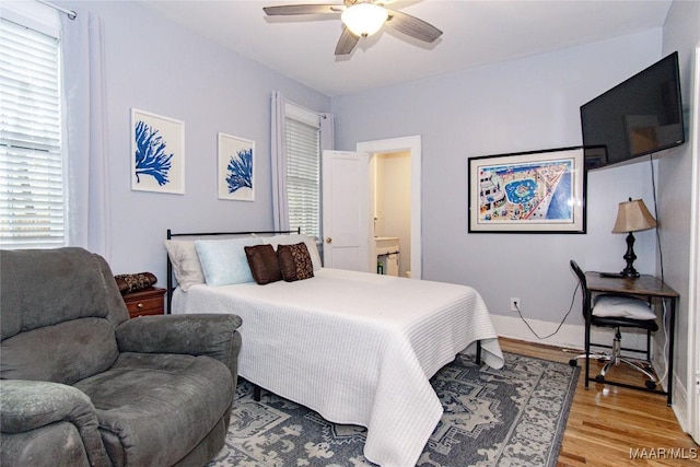 bedroom with light wood-style floors, a ceiling fan, and ensuite bathroom