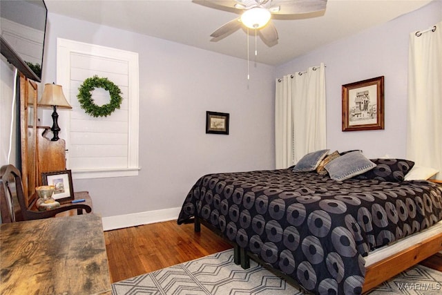 bedroom featuring wood finished floors, baseboards, and a ceiling fan