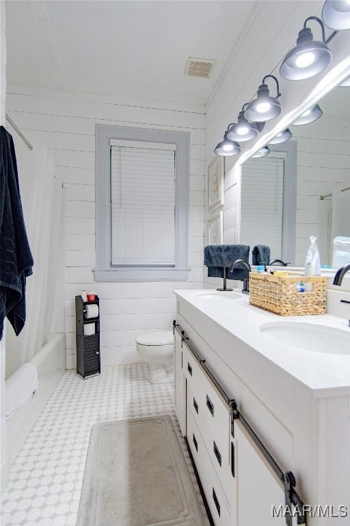 full bathroom with double vanity, toilet, shower / tub combo, and wood walls