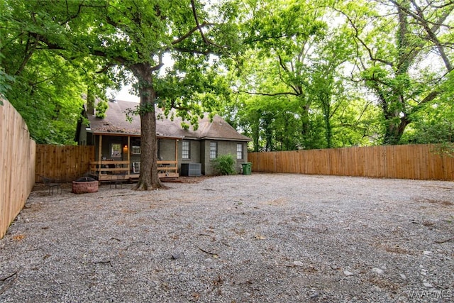 rear view of property featuring a fenced backyard and central AC
