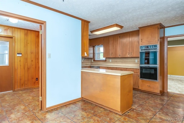 100 Duck Cv, Elmore, AL 36025 - kitchen with light countertops, tasteful backsplash, a peninsula, brown cabinets, and a textured ceiling