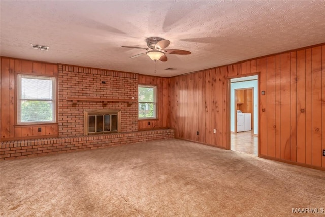 100 Duck Cv, Elmore, AL 36025 - unfurnished living room with a ceiling fan, wooden walls, carpet, a textured ceiling, and washer and dryer