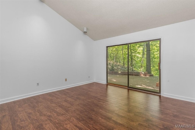 empty room with wood finished floors, vaulted ceiling, baseboards, and a textured ceiling
