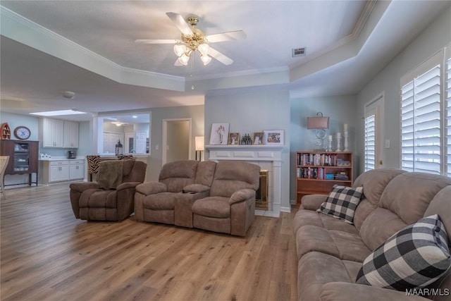 847 Dee Dr, Prattville, AL 36066 - living area with light wood-type flooring, a tray ceiling, a ceiling fan, a fireplace with flush hearth, and ornamental molding