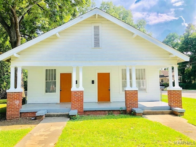 bungalow featuring covered porch and a front lawn