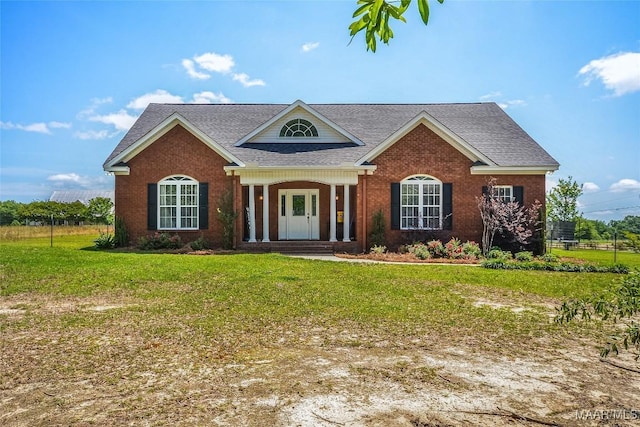 view of front of property featuring a front lawn, a shingled roof, and brick siding