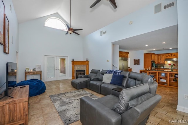 living room with a ceiling fan, high vaulted ceiling, and a tiled fireplace