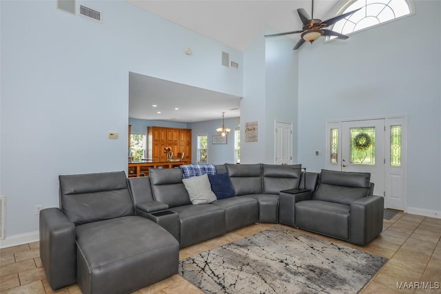 living room with a chandelier, a high ceiling, a ceiling fan, and baseboards