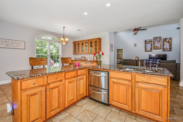 kitchen featuring a peninsula, open floor plan, a ceiling fan, dark stone countertops, and recessed lighting