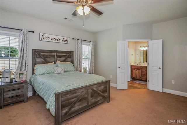bedroom featuring light colored carpet, baseboards, ensuite bath, and ceiling fan