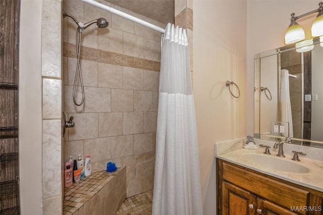 full bathroom with a tile shower and vanity