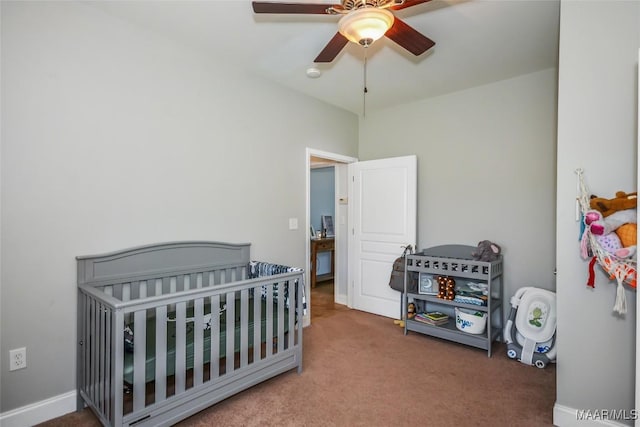 bedroom with carpet flooring, a crib, ceiling fan, and baseboards