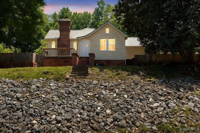 view of front of property featuring fence, metal roof, a chimney, and crawl space