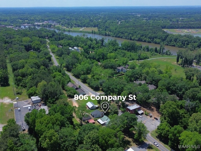 aerial view of property's location featuring a nearby body of water and a forest