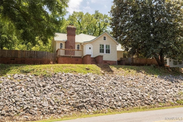 view of front of house featuring fence, metal roof, a chimney, and stairway