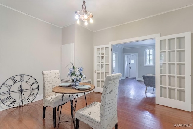 dining space with crown molding, a chandelier, wood finished floors, french doors, and baseboards