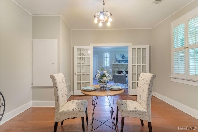 dining space featuring wood finished floors, crown molding, baseboards, and a chandelier