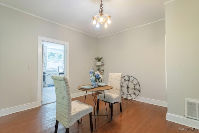 dining space with a chandelier, ornamental molding, baseboards, and wood finished floors