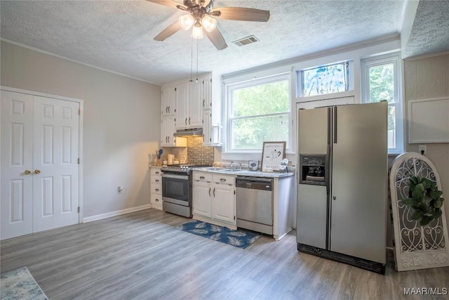 kitchen with appliances with stainless steel finishes, light wood-style floors, a textured ceiling, white cabinetry, and a ceiling fan