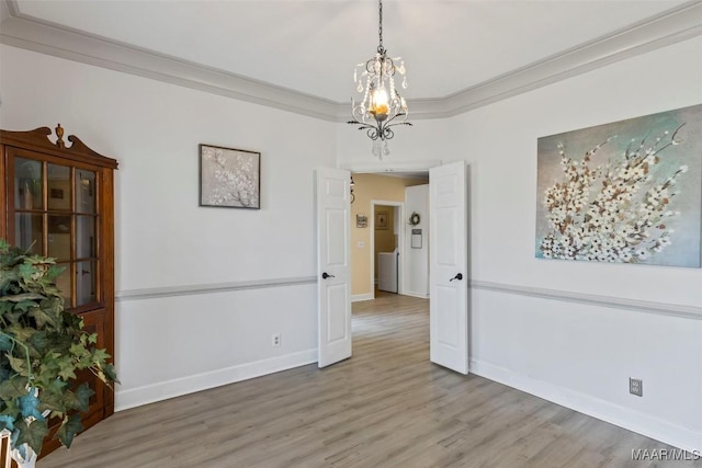 unfurnished room featuring light wood-style flooring, a chandelier, crown molding, and baseboards