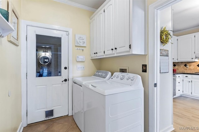 laundry room with cabinet space, washing machine and clothes dryer, crown molding, and light tile patterned floors