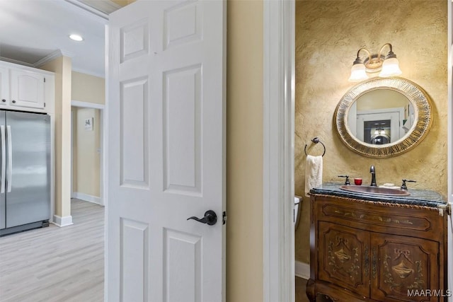 half bath featuring crown molding, wood finished floors, vanity, baseboards, and recessed lighting