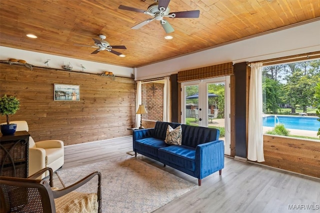 living area with wooden ceiling, wood walls, ceiling fan, french doors, and wood finished floors
