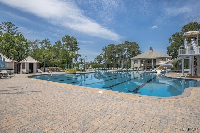 community pool featuring a water slide and a patio