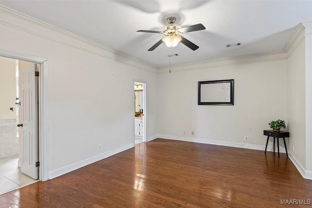 empty room with ceiling fan, ornamental molding, wood finished floors, and baseboards