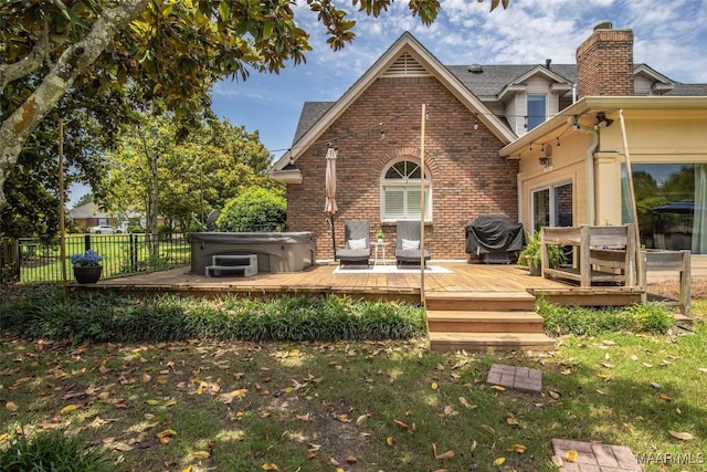 rear view of property featuring a hot tub, brick siding, fence, and a wooden deck