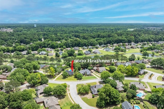 aerial view of residential area featuring a forest and a large body of water
