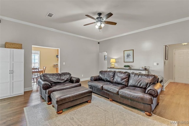 living area featuring wood finished floors, ceiling fan, crown molding, and baseboards