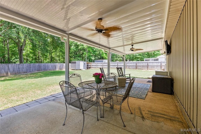 view of patio / terrace featuring a storage shed, outdoor dining area, an outdoor structure, and ceiling fan