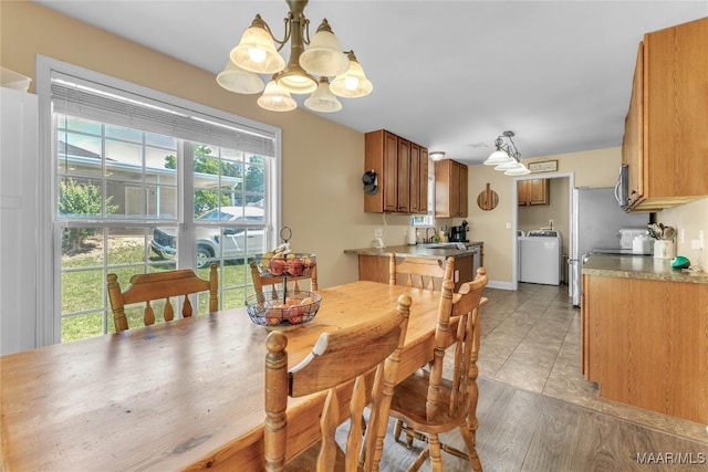 dining room featuring washer / dryer, a chandelier, and light tile patterned floors