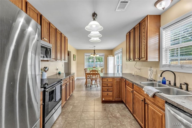 kitchen with stainless steel appliances, a sink, pendant lighting, and brown cabinetry