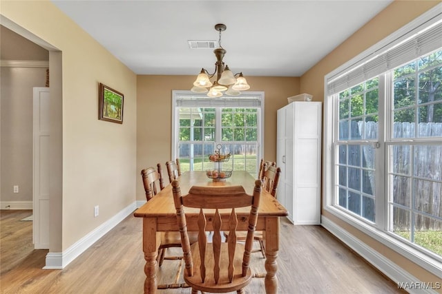dining room featuring light wood-type flooring, a chandelier, and baseboards