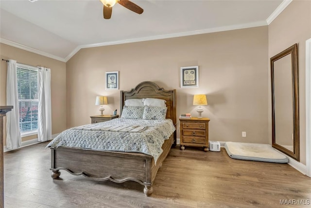 bedroom featuring wood finished floors, crown molding, a ceiling fan, baseboards, and lofted ceiling