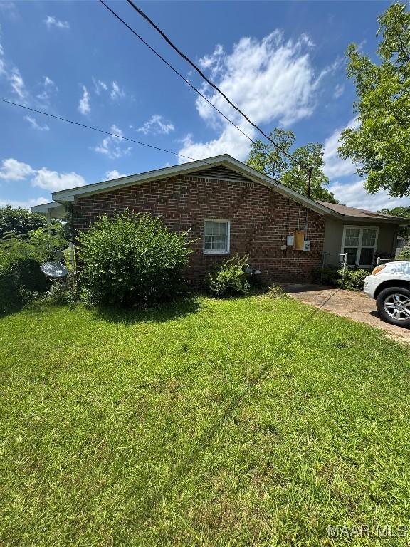 view of side of home featuring a yard and brick siding