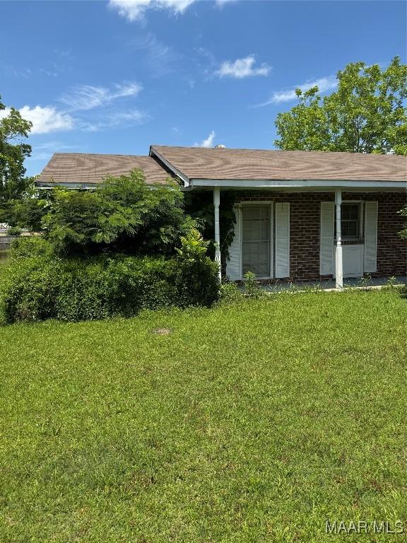 view of front of home with a front yard, a porch, and brick siding