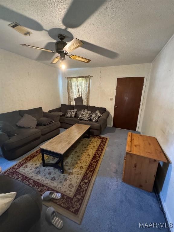 living area with ceiling fan, carpet floors, and a textured ceiling