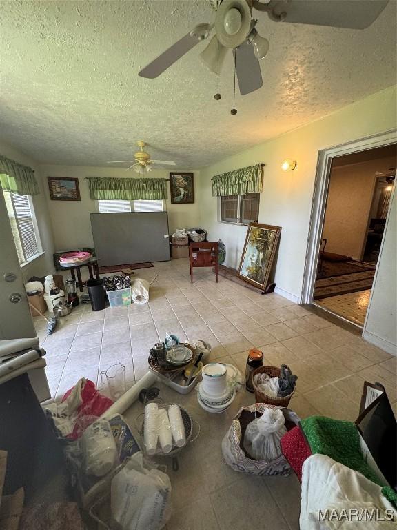living area featuring ceiling fan, a textured ceiling, and tile patterned flooring