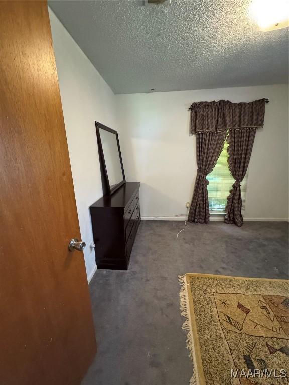unfurnished bedroom with carpet flooring, a textured ceiling, and baseboards