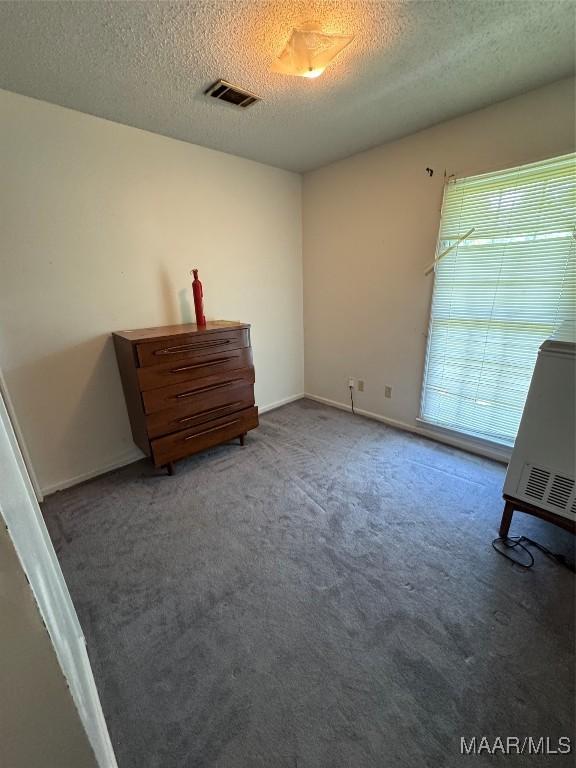 unfurnished bedroom with a textured ceiling, carpet floors, and baseboards