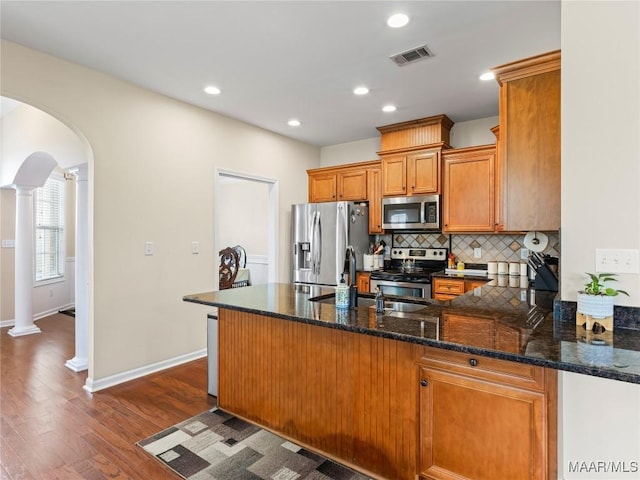 6812 Overview Ct, Montgomery, AL 36117 - kitchen featuring appliances with stainless steel finishes, decorative columns, arched walkways, a peninsula, and dark wood-type flooring