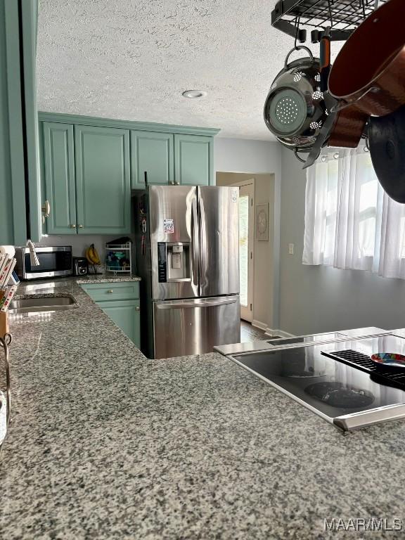 104 Carleton St, Prattville, AL 36067 - kitchen featuring stainless steel appliances, green cabinetry, healthy amount of natural light, stone countertops, and a textured ceiling