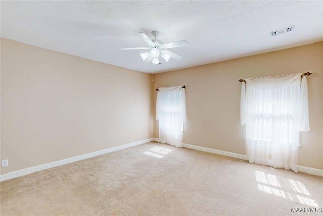 carpeted spare room featuring a ceiling fan and baseboards