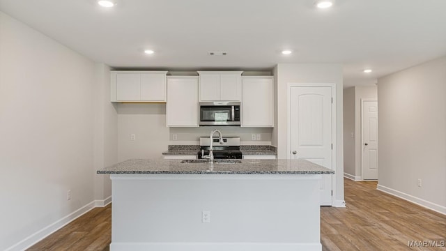 6004 Cunningham Trl, Montgomery, AL 36116 - kitchen featuring stainless steel appliances, a kitchen island with sink, white cabinetry, stone counters, and light wood-type flooring